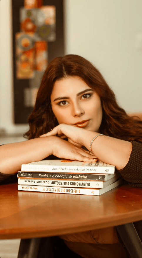 Taynara Oliveira apoiada sobre livros de autoestima e desenvolvimento